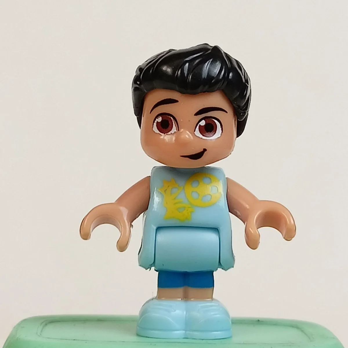 Yootz figure, male, short black hair, brown eyes, light medium blue shirt with yellow soccer ball flying throught a hoop pattern, blue shorts