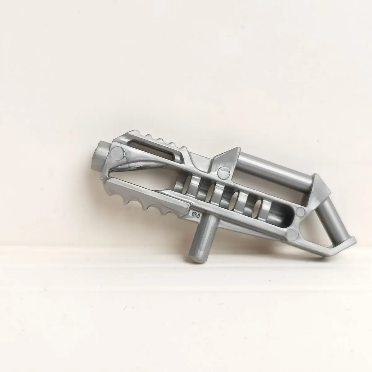 Minifigure Gun (Heavy laser blaster), with bar insert and handle on the back in Gray, Light (Metallic)