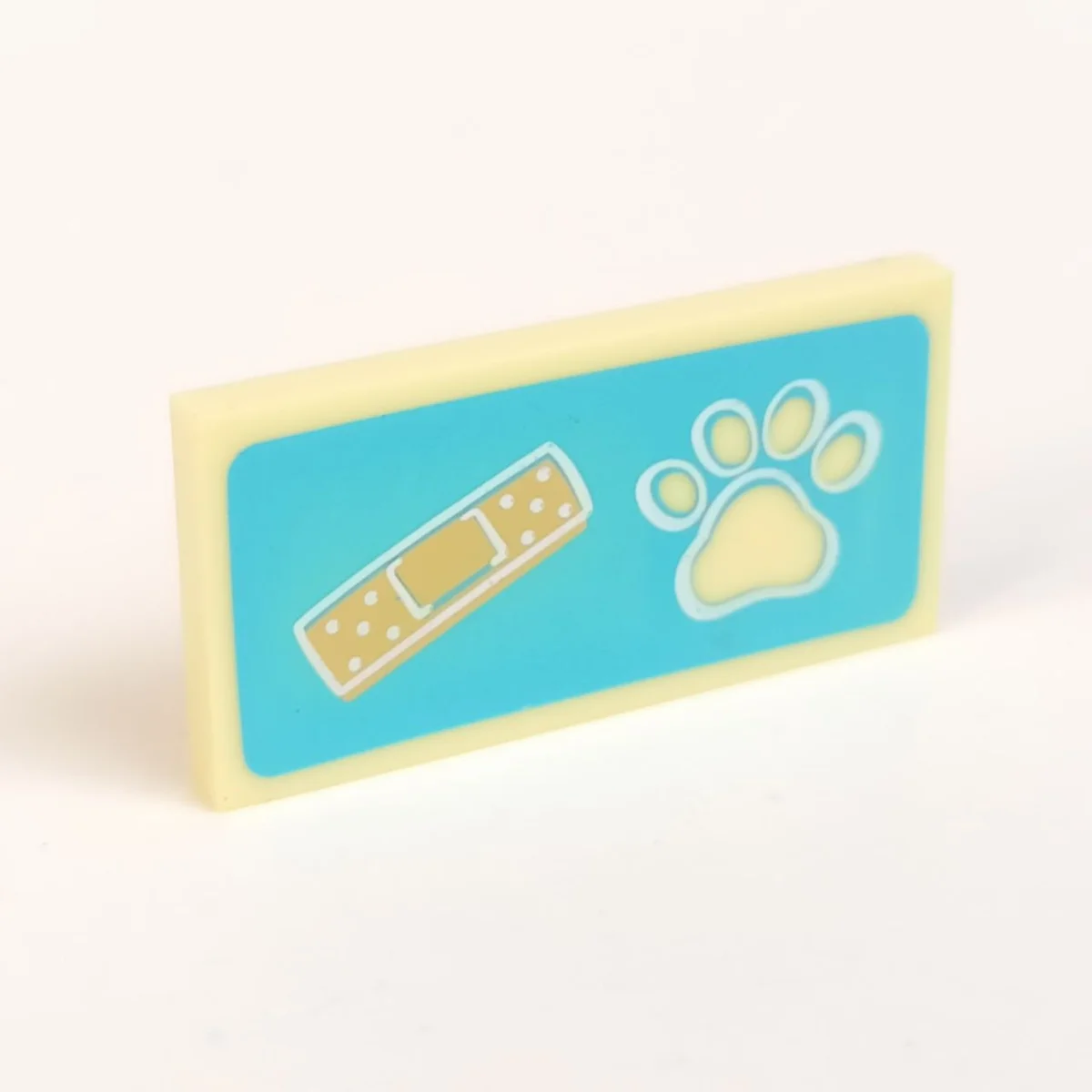 Tile 2 x 4 with brown, light tan bandaid and dog paw both in a stylized white outline on a azure background pattern in Yellow, Pastel